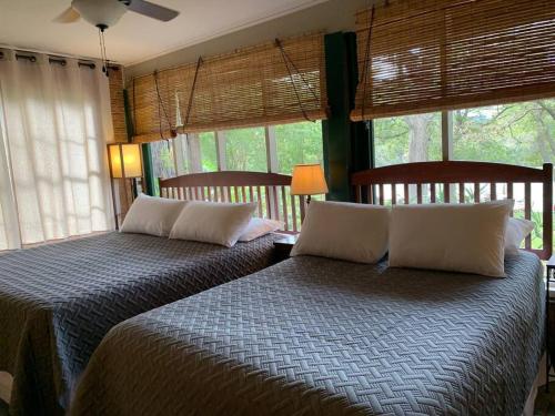 two beds sitting in a room with windows at The River Haven - Sleeps 32 - on Guadalupe River in Seguin