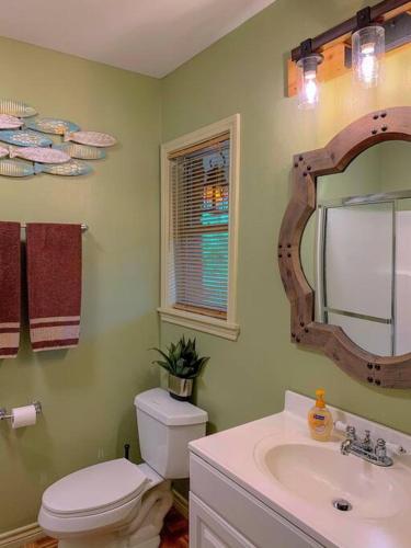 a bathroom with a toilet and a sink and a mirror at The River Haven - Sleeps 32 - on Guadalupe River in Seguin