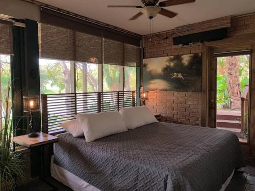 a bedroom with a bed with a ceiling fan and windows at The River Haven - Sleeps 32 - on Guadalupe River in Seguin