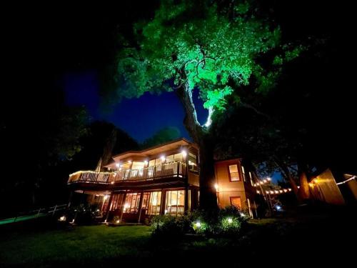 a house with a tree in front of it at night at The River Haven - Sleeps 32 - on Guadalupe River in Seguin