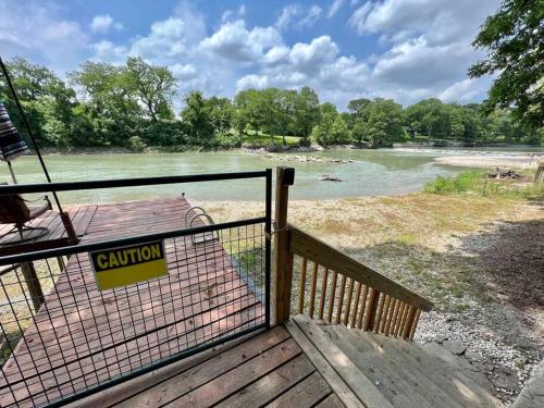a deck with a fence with a view of a river at The River Haven - Sleeps 32 - on Guadalupe River in Seguin