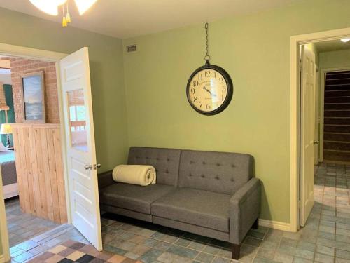 a couch in a living room with a clock on the wall at The River Haven - Sleeps 32 - on Guadalupe River in Seguin
