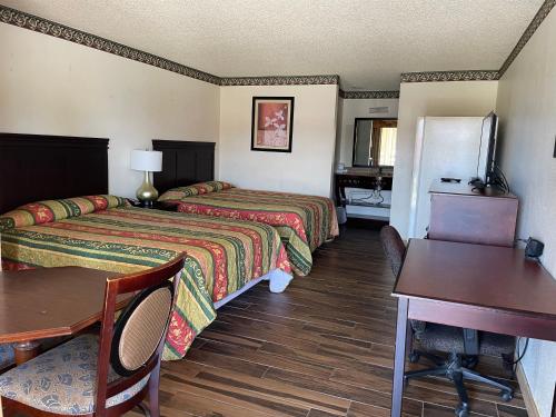 a hotel room with two beds and a desk at Granbury Inn and Suites in Granbury