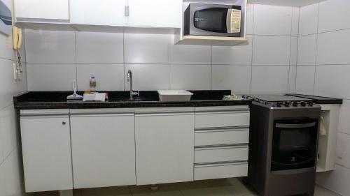a kitchen with a sink and a microwave at Beach Class Convention - Flats em Boa Viagem por Yolo in Recife