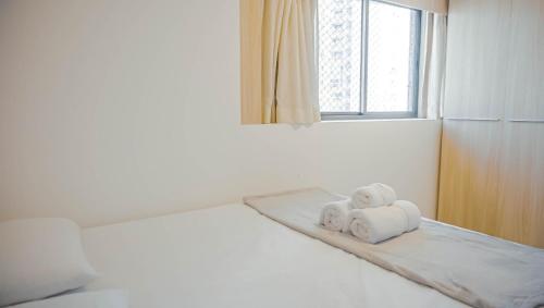 two towels sitting on a bed in a room with a window at Beach Class Convention - Flats em Boa Viagem por Yolo in Recife