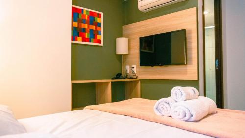 a bedroom with a bed with towels and a television at Beach Class Convention - Flats em Boa Viagem por Yolo in Recife