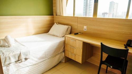 a small bedroom with a bed and a desk at Beach Class Convention - Flats em Boa Viagem por Yolo in Recife