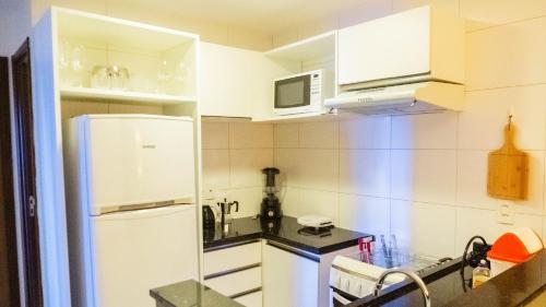 a kitchen with white cabinets and a white refrigerator at Beach Class Convention - Flats em Boa Viagem por Yolo in Recife