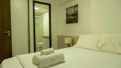 a bedroom with a white bed and a bathroom at Beach Class Convention - Flats em Boa Viagem por Yolo in Recife