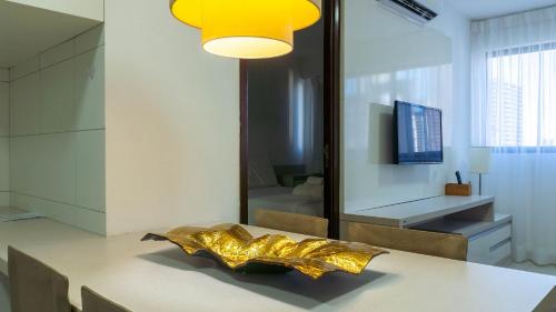 a dining room with a table with a gold object on it at Beach Class Convention - Flats em Boa Viagem por Yolo in Recife