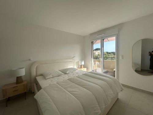 a white bedroom with a large bed and a mirror at Clos d'Alice Villa 3 in Sainte-Maxime