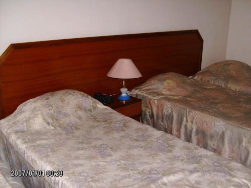 a hotel room with two beds and a lamp on a table at Olhos Pretos in Caldas da Rainha