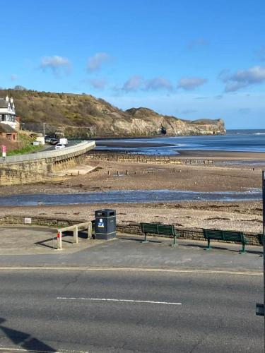 a road with benches on the side of a beach at Turnstone Cottage in Whitby