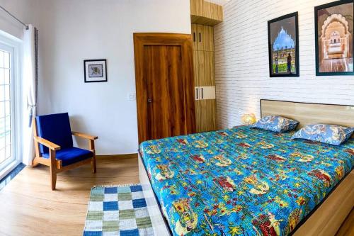 a bedroom with a bed and a blue chair at Comfort & Cozy, Villa in Orchha