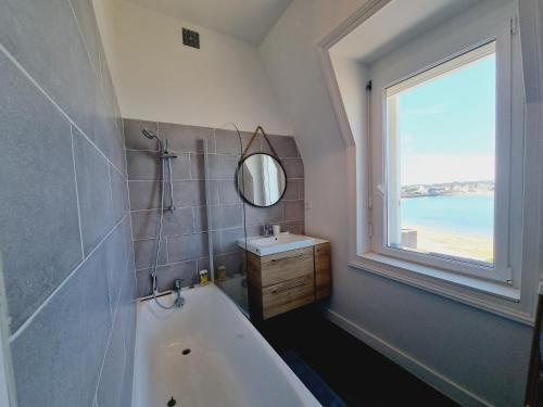 une salle de bain avec une baignoire, un lavabo et une fenêtre dans l'établissement Belle vue sur les sablons, à Saint-Malo