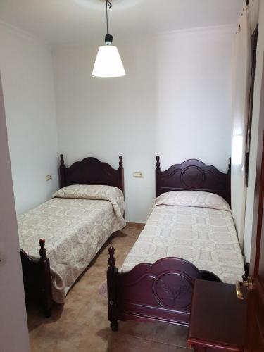 a bedroom with two beds and a pendant light at Matalascañas MAR in Matalascañas