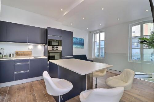 une cuisine avec des armoires bleues et des chaises blanches dans l'établissement Havre de paix & Jardin Quartier Bonsecours Fibré, à Trouville-sur-Mer