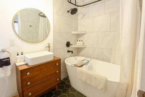 a bathroom with a tub and a sink and a mirror at Classic & Cozy Apartments - Parking & Close To Dw in Medford