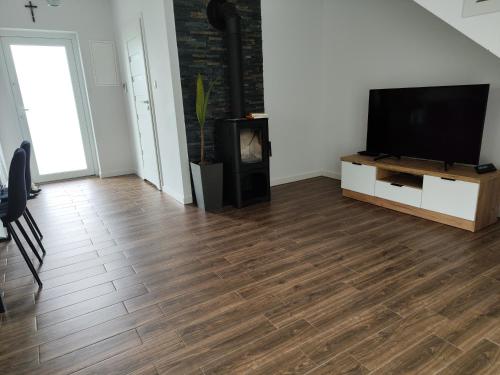 a living room with a flat screen tv and a wooden floor at Noclegi i ApiTerapia Pszczeli Raj in Huta Szklana
