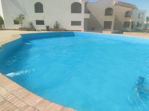 a large blue swimming pool in front of a building at قرية منيه فايد in ‘Ezbet Hasan Sallâm