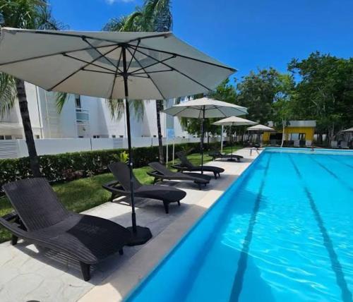 une piscine avec des chaises et des parasols à côté d'une piscine dans l'établissement Casa Espiral, à Playa del Carmen