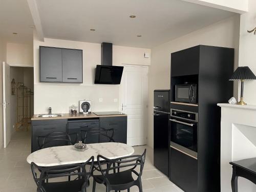 a kitchen with black appliances and a table and chairs at Les Moulins Saint Antoine in Loches