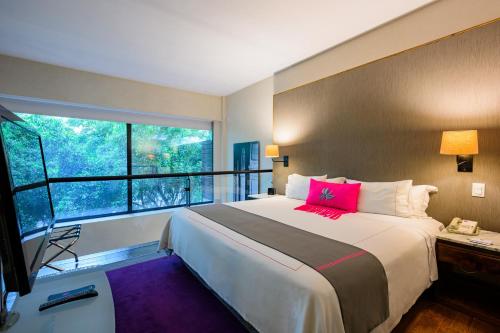 a bedroom with a large bed with a large window at Las Suites Campos Eliseos in Mexico City