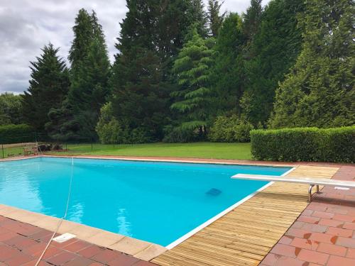 une piscine bleue avec une terrasse en bois et des arbres dans l'établissement Sur Chateau La Mothe, à Peyrilhac
