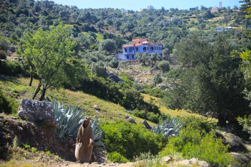 a woman sitting on a hill in front of a house at Haven Hills Social Club in Chefchaouene