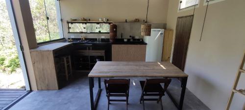 a kitchen with a table and chairs and a refrigerator at Studio Pitanga - Vale do Capão - Caeté Açu - in Vale do Capao