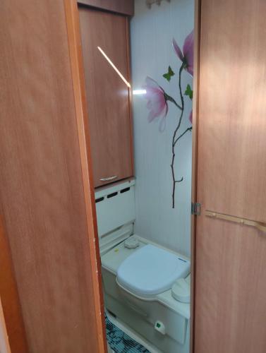 a bathroom with a toilet with a flower on the wall at Countryside Relax in Liepupe