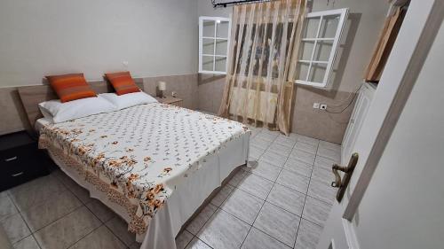 a bedroom with a bed with orange pillows and a window at 35m2 apt close to beach in Lygia