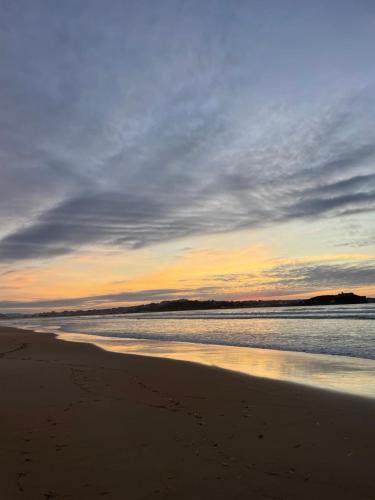 a beach with a cloudy sky and the ocean at Bahía de Pedreña 2 in Pedreña