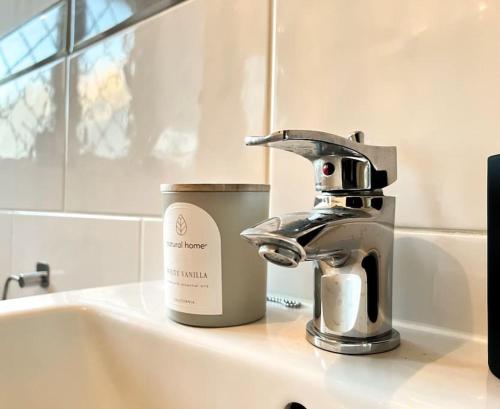 a sink with a faucet and a cup on it at Simple House w- FREE PARKING by Manchester Airport - FREE DROP-OFF in Manchester