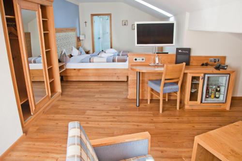 a living room with a bed and a desk with a television at Hotel am Wiesenhang - Garni in Bad Kohlgrub