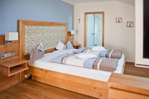a bedroom with a large bed with a wooden headboard at Hotel am Wiesenhang - Garni in Bad Kohlgrub