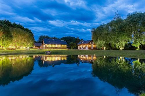 a house by the water at night at Dobilyne Homestead in Gražiškiai