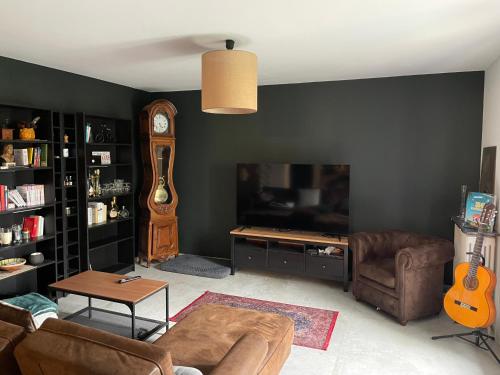 - un salon avec un canapé, une télévision et une guitare dans l'établissement Maison 5min du centre ville, à Avignon