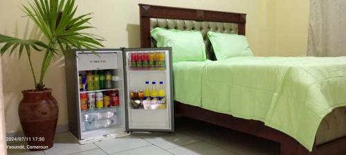 a bedroom with a large bed with a drink refrigerator at AFRIEUROTEXT Kamerun-High Standing-Appartements-Wifi-Security-Restaurant-modern Kitchen in Yaoundé