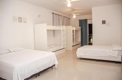 two beds in a bedroom with white walls at Sua Casa em Maresias I in São Sebastião