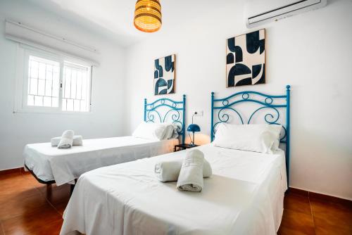 2 Betten in einem weiß-blauen Zimmer in der Unterkunft Escuela Village in Marbella