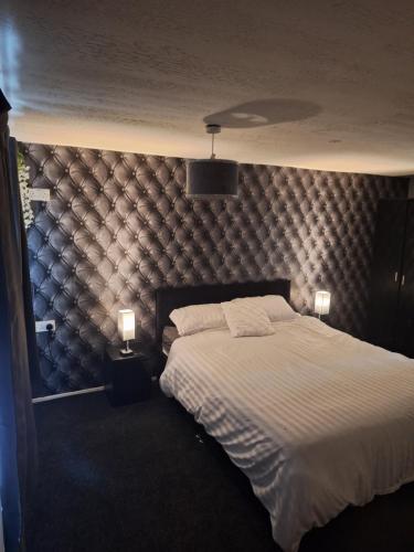 a bedroom with a large bed with a padded wall at Sunnyside in Kinmel Bay