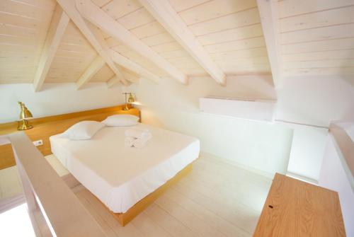 a bedroom with a white bed and wooden ceilings at NOIMA Casa Unico in Megalochori