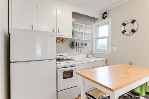 a white kitchen with a table and a refrigerator at Bayfront East Quogue Retreat with Private Boat Dock in East Quogue