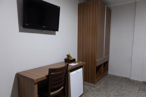 a room with a desk with a television on the wall at BOMBONATO HOTEL - Fácil Acesso ao Aeroporto e parque de Exposições ABCZ in Uberaba