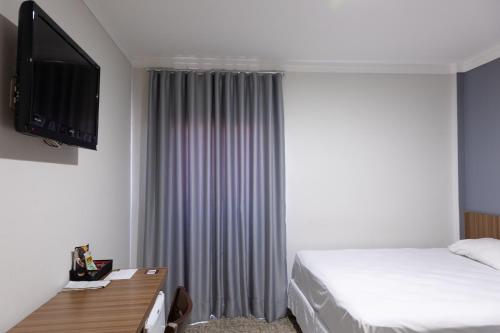 a hotel room with a bed and a flat screen tv at BOMBONATO HOTEL - Fácil Acesso ao Aeroporto e parque de Exposições ABCZ in Uberaba