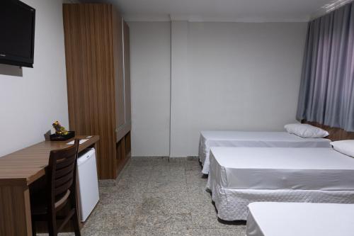 a hotel room with two beds and a television at BOMBONATO HOTEL - Fácil Acesso ao Aeroporto e parque de Exposições ABCZ in Uberaba