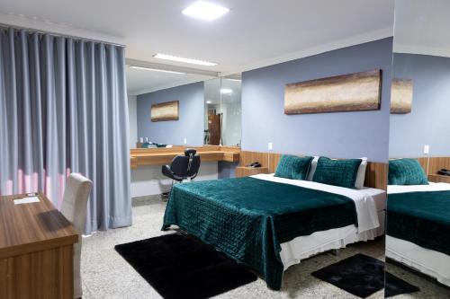 a hotel room with two beds and a desk at BOMBONATO HOTEL - Fácil Acesso ao Aeroporto e parque de Exposições ABCZ in Uberaba