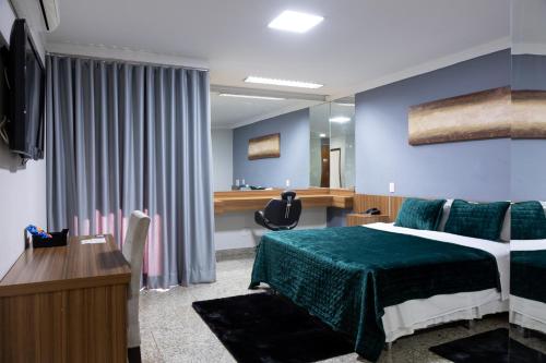 a bedroom with a bed and a desk and a mirror at BOMBONATO HOTEL - Fácil Acesso ao Aeroporto e parque de Exposições ABCZ in Uberaba