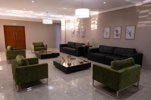 a living room with black couches and green chairs at BOMBONATO HOTEL - Fácil Acesso ao Aeroporto e parque de Exposições ABCZ in Uberaba